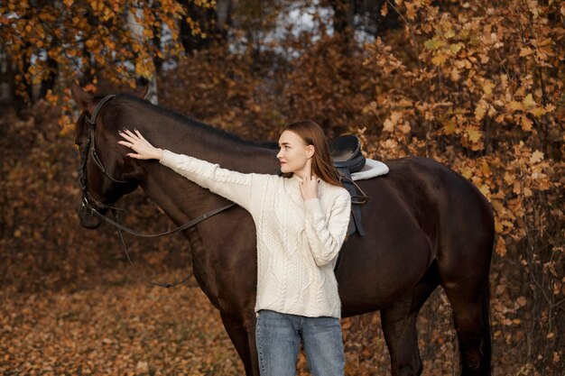 Une fille avec un cheval dans la nature, une promenade d'automne avec un animal