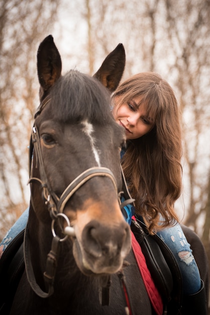 Fille avec un cheval sur ranch onn automne nuageux.