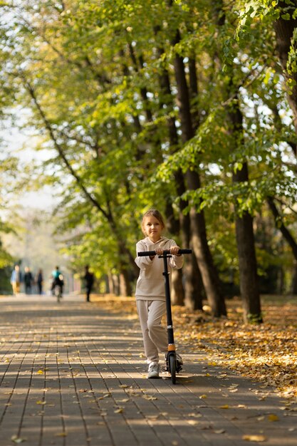 Fille chevauchant un scooter dans le parc