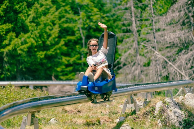 Une fille chevauche des montagnes russes de montagne et des vagues Environnement de montagne avec des arbres en arrière-plan