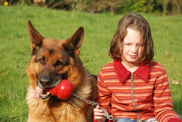 Photo une fille avec un chien assise sur l'herbe dans le parc