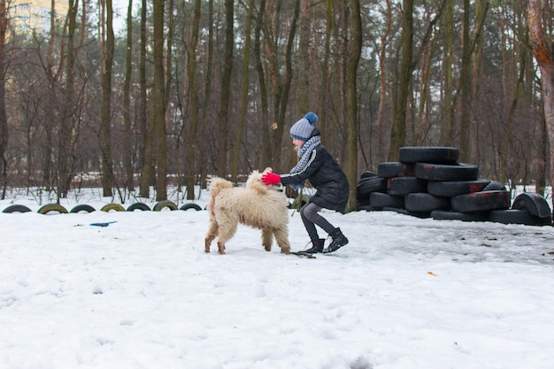 Une fille et un chien caniche royal en hiver