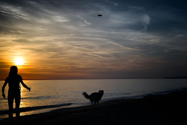 Fille avec chien et frisbee à la mer