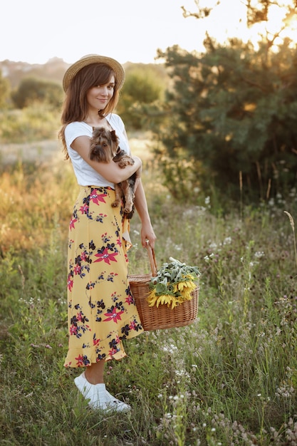 Fille avec chien et panier pique-nique sur promenade au coucher du soleil d'été