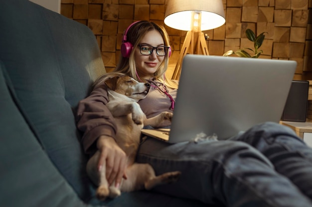 Une fille avec un chien regardant un film sur un ordinateur portable avec des écouteurs Animaux et amis pour les personnes