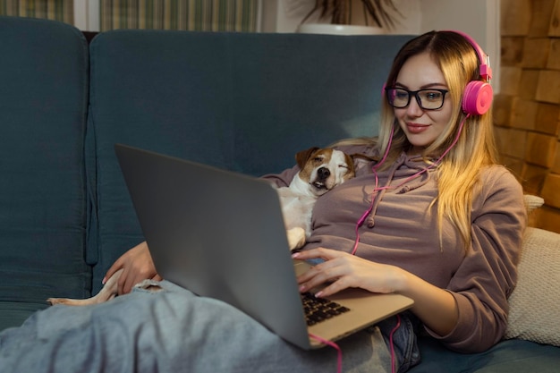 Une fille avec un chien regardant un film sur un ordinateur portable avec des écouteurs Animaux et amis pour les personnes