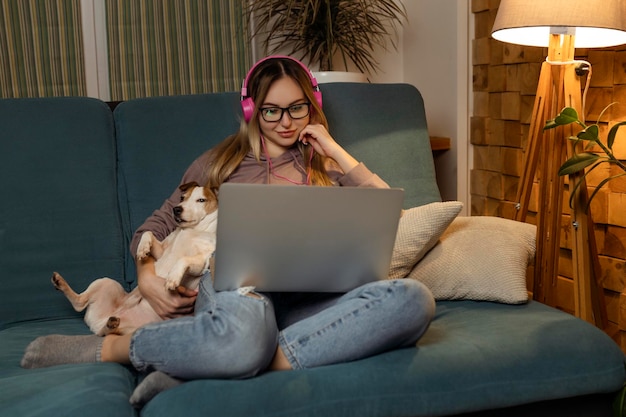 Une fille avec un chien regardant un film sur un ordinateur portable avec des écouteurs Animaux et amis pour les personnes