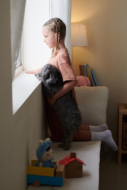 Fille et chien regardant par la fenêtre