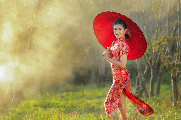 Fille chinoise avec une robe traditionnelle Cheongsam dans le jardin