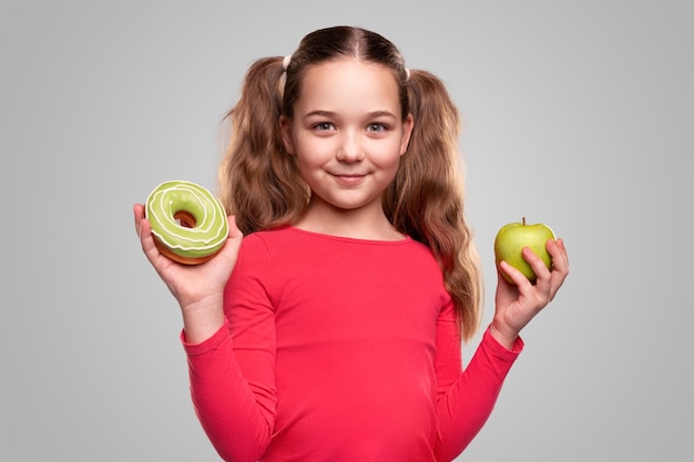 fille choisissant entre pomme verte et beignet