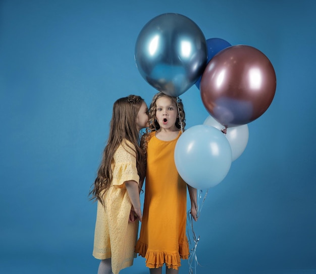 Une fille chuchote quelque chose à l'oreille d'une autre fille avec des ballons