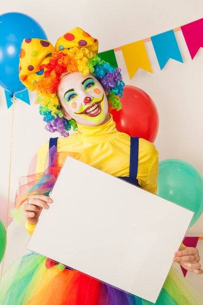 Photo fille de clown en vacances tenant une assiette blanche pour les inscriptions