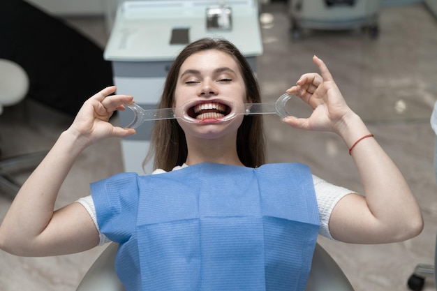 Fille Avec Des Coiffes Dentaires Assise Dans Le Cabinet Du Médecin Pour Une Procédure De Blanchiment Des Dents. Procédure En Dentisterie. Blanchiment Des Dents Aux Ultraviolets