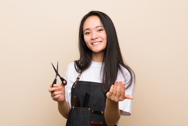 Fille de coiffeur adolescent invitant à venir avec la main. Heureux que tu sois venu