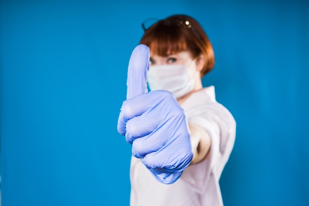 Fille en combinaison médicale et gants montre les pouces vers le haut