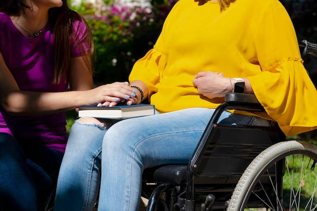 Fille consolant sa mère assise dans un fauteuil roulant avec un livre