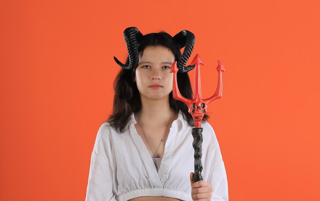 une fille avec des cornes de démon d'Halloween sur un fond orange