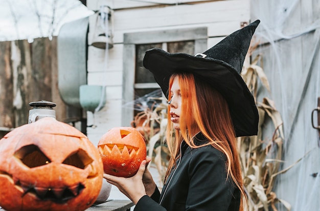 Une fille en costume de sorcière s'amusant à une fête d'Halloween sur le porche décoré