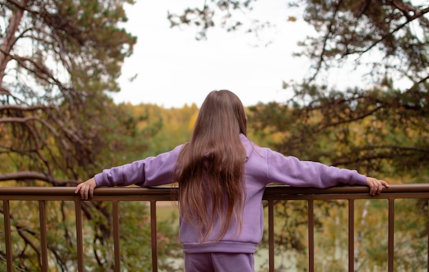 Une fille en costume violet aux cheveux longs inhale de l'air frais en automne dans la forêt Le concept de respiration inhalant relaxant