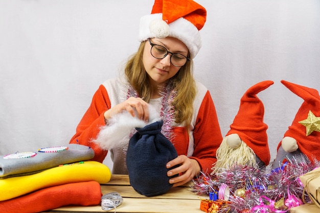 La fille coud un gnome de Noël.