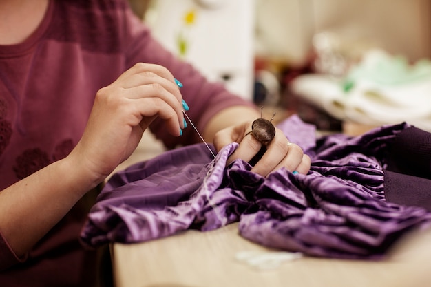 La fille coud une robe, les mains se ferment