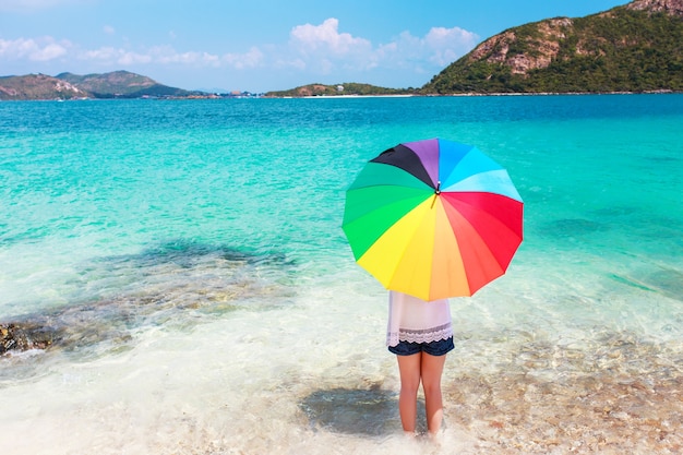 fille avec couleur parapluie complet sur la plage de sable