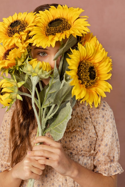 Fille de coup moyen tenant des tournesols