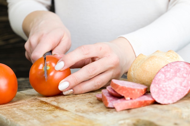 La fille coupe la viande et les tomates