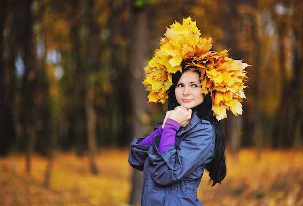Fille avec une couronne de feuilles jaunes sur la tête sur le fond de la forêt d&#39;automne