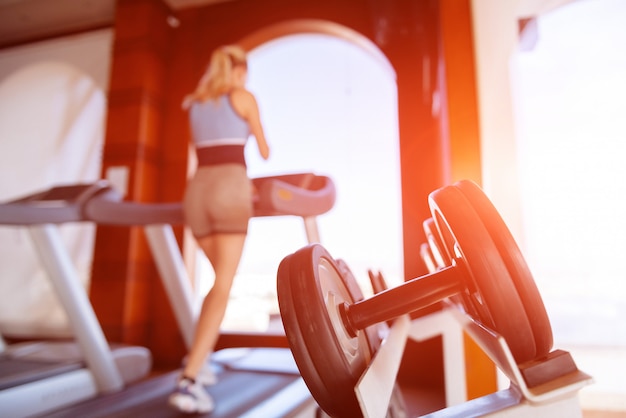 Fille sur la course du matin sur le tapis roulant dans la salle de gym devant une grande fenêtre sur le fond de la mer