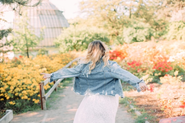 Photo fille court à l'extérieur des arbres en fleurs du jardin de printemps