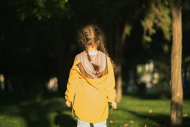 La fille court sur la pelouse verte dans les rayons du coucher du soleil