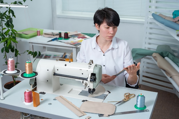 Fille de couturière est sur le lieu de travail derrière la machine à coudre