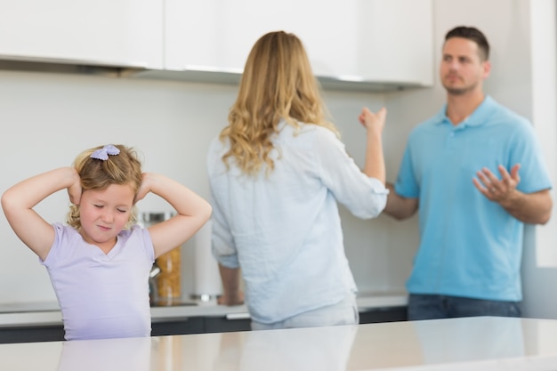 Fille couvrant les oreilles pendant que les parents se disputent