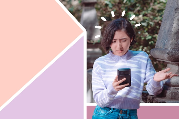 Photo une fille créative est debout et regarde son téléphone portable a une expression de colère espace libre pour le texte