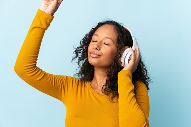 Fille cubaine adolescente isolée sur fond bleu, écouter de la musique et de la danse