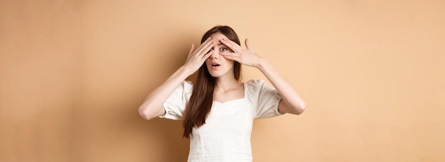 Une fille curieuse qui regarde à travers les doigts quelque chose d'intéressant a hâte de voir l'intri