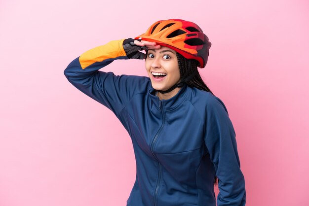 Photo fille cycliste adolescente isolée sur fond rose faisant un geste de surprise tout en regardant sur le côté