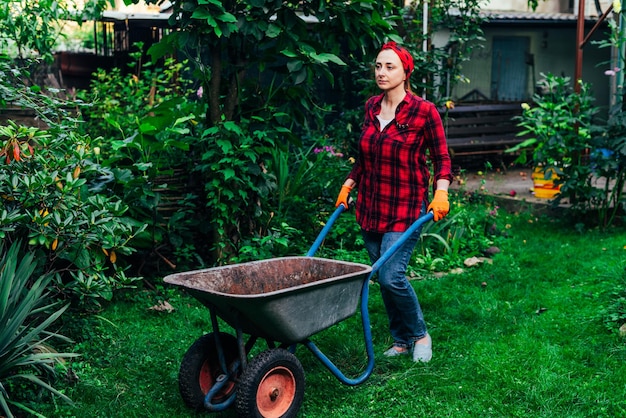 Une fille dans un bandana rouge et une chemise récolte dans le jardin et le jardin de légumes