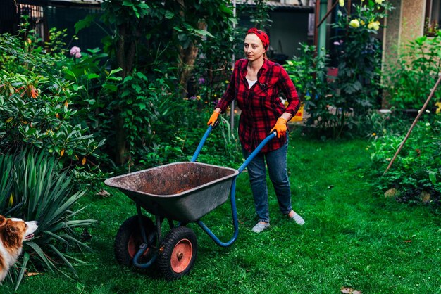 Une fille dans un bandana rouge et une chemise récolte dans le jardin et le jardin de légumes