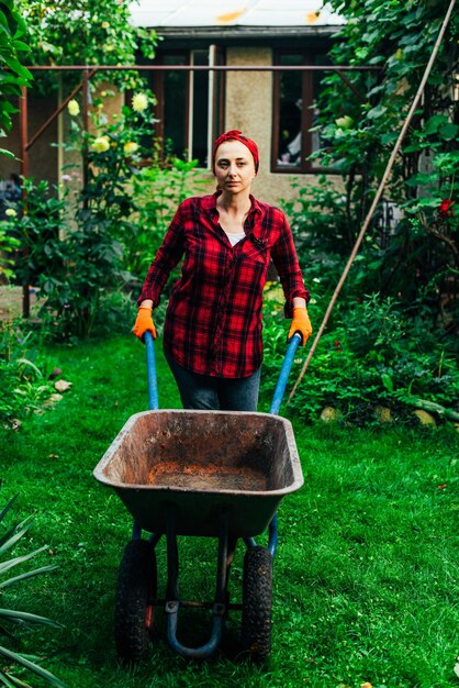 Une fille dans un bandana rouge et une chemise récolte dans le jardin et le jardin de légumes