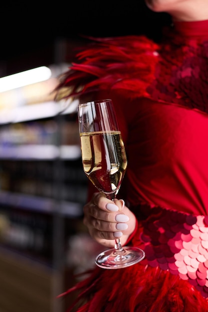 Une fille dans une belle robe rouge tient un verre de champagne dans ses mains