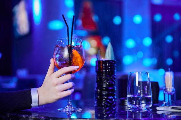 Une fille dans une boîte de nuit tient un verre avec un cocktail alcoolisé à la main