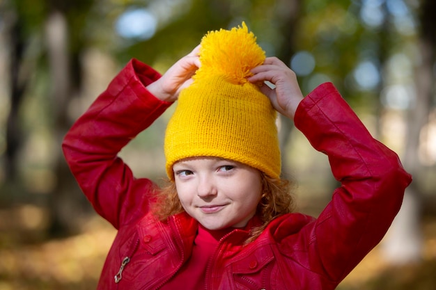 Fille dans un bonnet tricoté jaune en automne Portrait d'un enfant dans le parc en automne