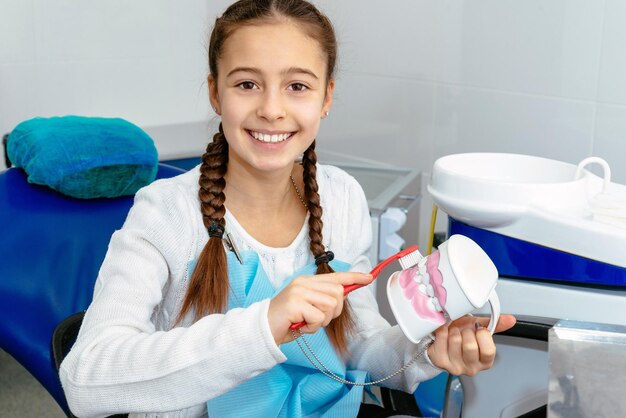 Photo fille dans le bureau du dentiste montre comment se brosser les dents