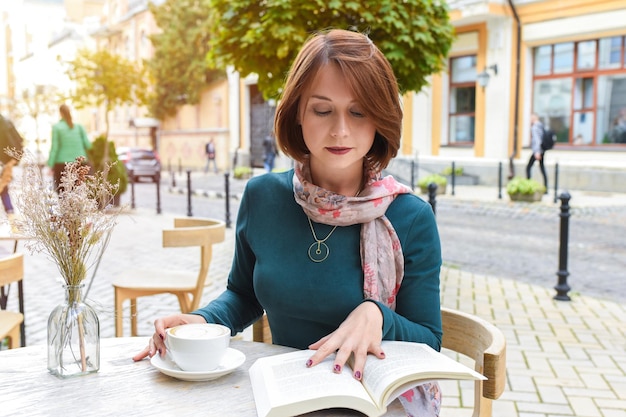 Une fille dans un café lit un livre et boit du café