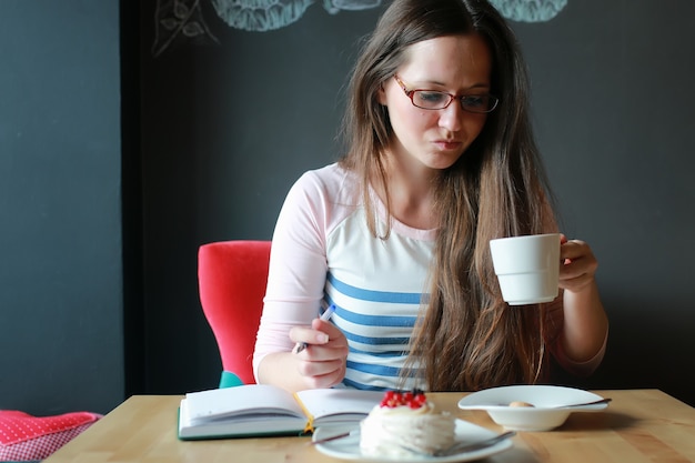 Fille dans un café pour une tasse de café avec le cahier