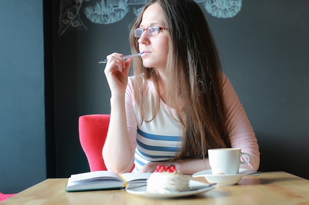 Fille dans un café pour une tasse de café avec le cahier