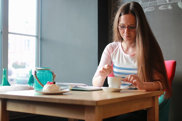 Fille dans un café pour une tasse de café avec le cahier