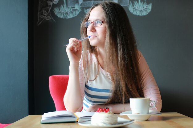 Fille dans un café pour une tasse de café avec le cahier